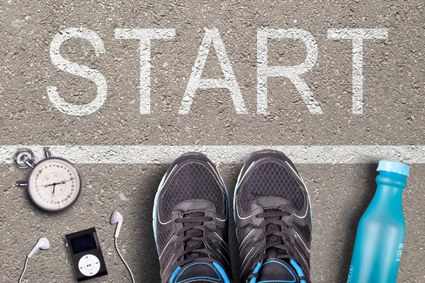 Men Running shoes and equipment on asphalt whit start inscription. Running training on hard surfaces. Runner Equipment stopwatch and music player and plastic water bottle. Asphalt on background.