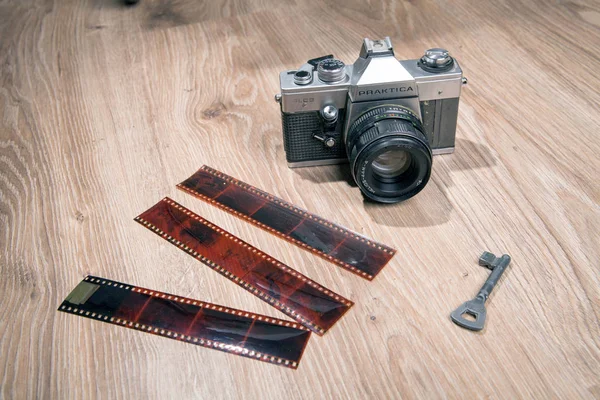 旧的模拟相机 Praktica Plc 上的木材背景 相机与一个短的表带 复古嬉皮士风格 桌子上的钥匙 — 图库照片