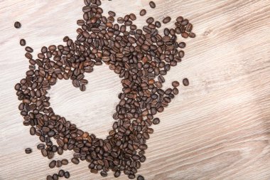 Kalp ahşap masa arka plan üzerinde beyaz kahve çekirdekleri yapmak.