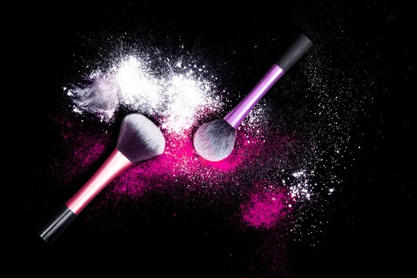 Makyaj fırçaları ile renkli toz glitter toz siyah arka plan üzerine döktüm. Yeni yıl partisi parlak renklerle makyaj fırça. Beyaz ve pembe toz.