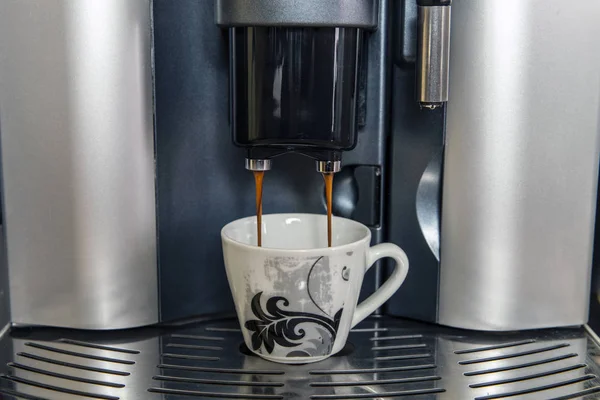 Coffee maker with cup of espresso. Filling the coffee cup in the coffee machine.