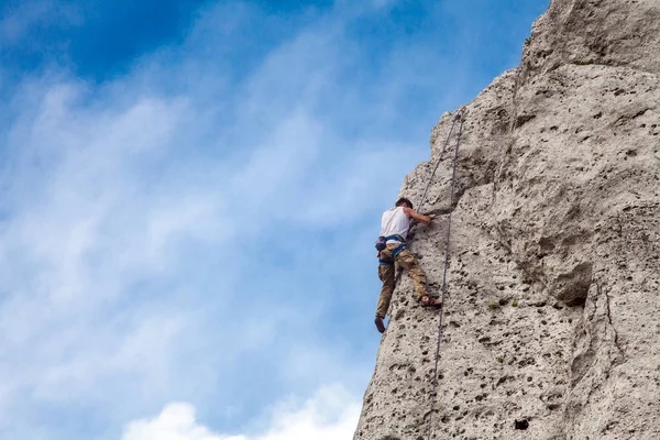 Man climbs to the top of the mountain. Rock climbing with belaying. Learning to climb a mountain. To reach a top.