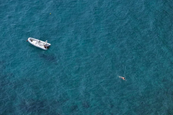 Vue aérienne d'un nageur et d'un bateau de vitesse blanc sur une eau de mer bleu clair — Photo