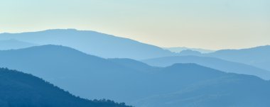 Gün batımında güneş ışınlarının ufuktan dağlar üzerinde mavi tonları