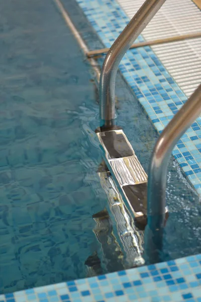 Canto de uma piscina com água limpa e escadas verticais — Fotografia de Stock