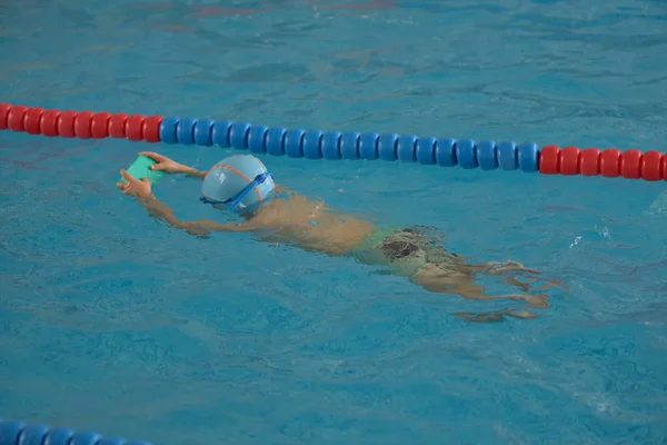 Glad lille dreng lære at svømme i en indendørs pool - Stock-foto