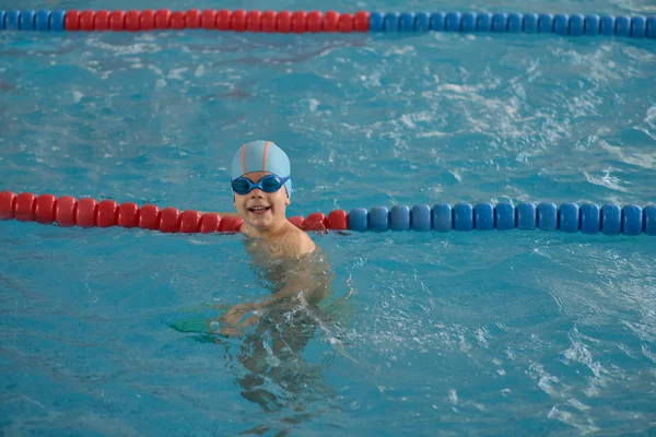 Happy little boy learning to swim in an indoor pool