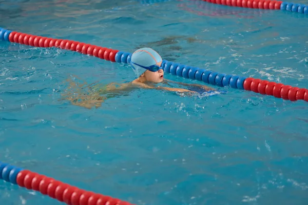 Счастливый маленький мальчик учится плавать в закрытом бассейне — стоковое фото