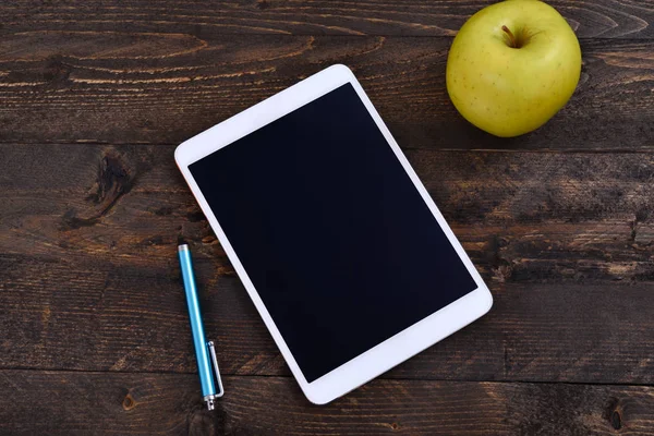 Weißes digitales Tablet mit schwarzem Bildschirm auf Holztisch, mit Tablet-Stift und Apfel — Stockfoto