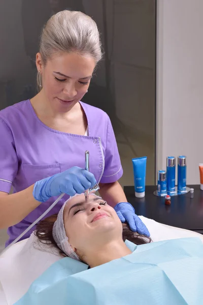Mooie jonge vrouw krijgt professionele huidbehandeling in een kliniek schoonheid — Stockfoto