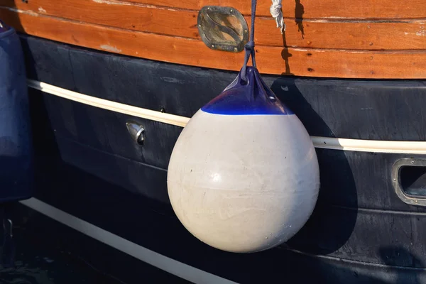 A Fender (boating) hanging on the board to protect the side of the sailing vessel from the damage. Italy. — Stock Photo, Image