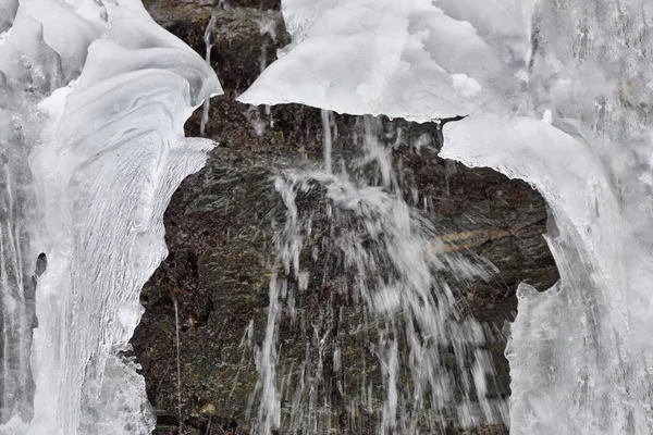 Ice icicles hang on mountain rocks in a cold winter day with wat — Stock Photo, Image
