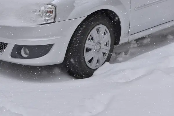 Автомобиль с зимними шинами на заснеженной дороге — стоковое фото