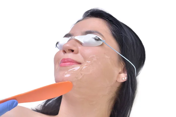 Hermosa mujer joven acostada en una mesa con gafas protectoras en los ojos recibiendo un tratamiento de piel láser —  Fotos de Stock