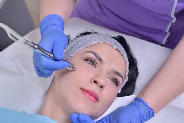 Mooie jonge vrouw krijgt professionele verjonging gezichtshuid behandeling in een kliniek professionele schoonheid — Stockfoto