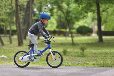 Mutlu çocuk çocuk 5 yıllık güzel bahar gününde bir bisiklet ile açık parkta eğleniyor. Etkin alt spor yapma. Emniyet Spor Eğlence çocuk kavramı ile