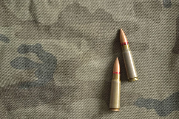 Two rifle bullets on military camo. Military ammunition — Stock Photo, Image