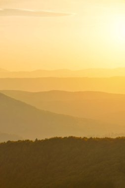 Gün batımında güneş ışınlarının ufuktan dağlar üzerinde altın tonları