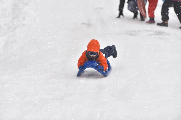 Liten pojke som rider på snö glider vintertid — Stockfoto