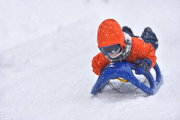 Liten pojke som rider på snö glider vintertid — Stockfoto