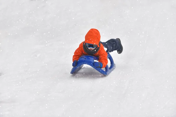 Liten pojke som rider på snö glider vintertid — Stockfoto