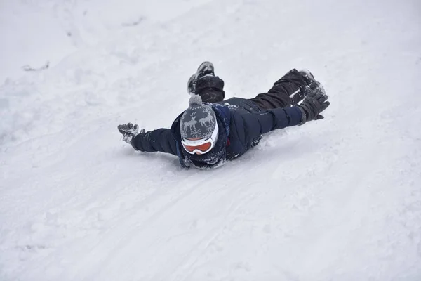 Menino desliza na neve no tempo de inverno — Fotografia de Stock