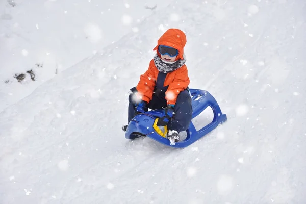 Petit garçon chevauchant sur des glissades de neige en hiver — Photo
