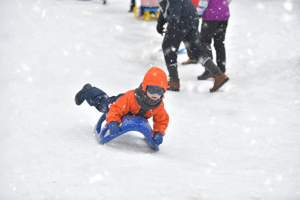 Liten pojke som rider på snö glider vintertid — Stockfoto