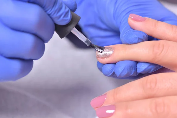 Nail Care och manikyr. Närbild av vackra kvinnliga händer tillämpa genomskinligt nagellack på hälsosam naturlig kvinnas naglar i skönhetssalong. Manikyr Hand målning kunds naglar. Hög upplösning — Stockfoto