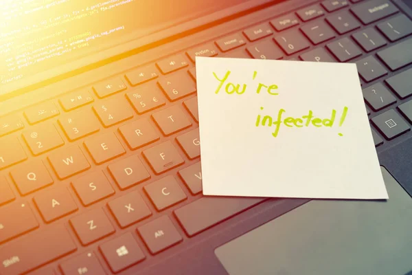 You\'re infected message concept written post it on laptop keyboard