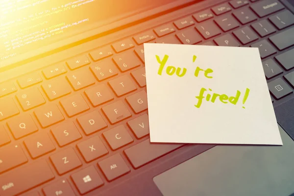 You\'re fired message concept written post it on laptop keyboard