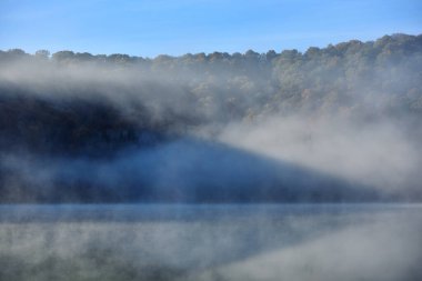 Romanya 'nın St. Ana gölündeki sulara yansıyan ağaçlarla dağlarda sonbahar manzarası