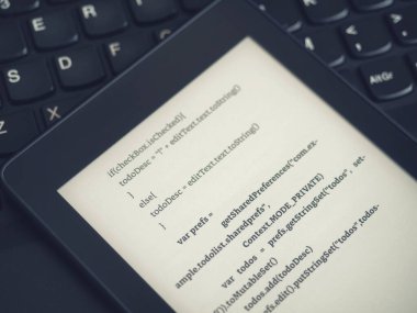 Bir kodlama okulunda dizüstü bilgisayar klavyesinde programlama dersleri alan bir kitap okuyucusunun yüksek görünümü