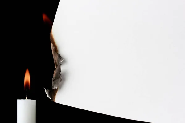 Burning paper with candle on a black background
