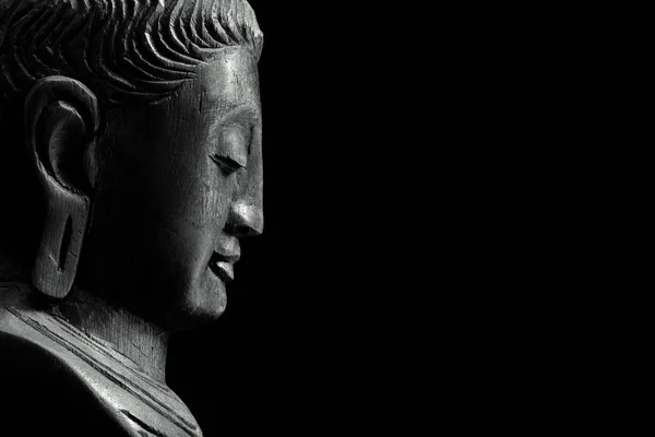 Siyah bir arka plan üzerinde izole ahşap Buda'nın profili.