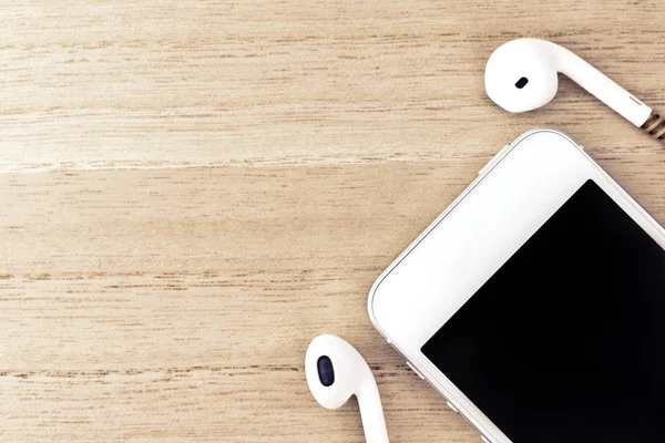Üstten Görünüm, akıllı telefon ve kulaklık üzerinde ahşap arka plan kopya alanı ile.