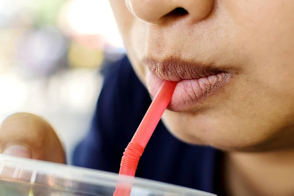Closeup Mouth of asian woman with drinking water with a suction tube.