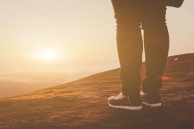 Gün batımında dağın zirvesinde duran genç kadın.