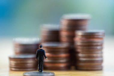 Minyatür iş adamını kapat ve para destesine bak. İş finansmanı büyüme kavramı.