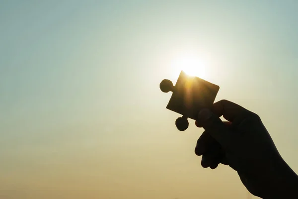 Silueta rukou držících část skládačky při západu slunce backgro — Stock fotografie