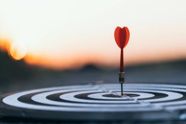 Kırmızı dart okunu kapat ve günbatımı arka planındaki hedef dart tahtasına vur. İş hedefleme ve odaklanma kavramı