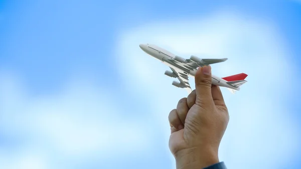 Joven asiático celebración miniatura juguete avión vuelo en nube azul — Foto de Stock