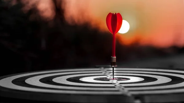 Close up red dart arrow hitting target center dartboard on sunse — Stock Photo, Image