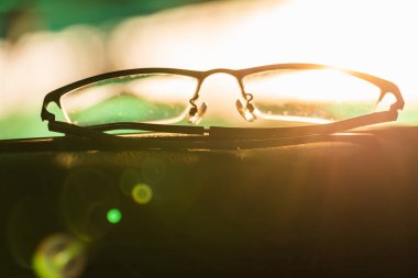 Close-up glasses with camera flare at sunrise blurred background