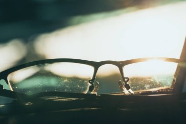 Close-up glasses with camera flare at sunrise blurred background