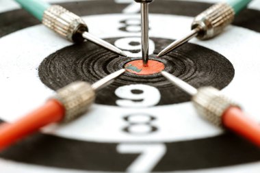 Close-up dart arrow hitting target centre dartboard background. 