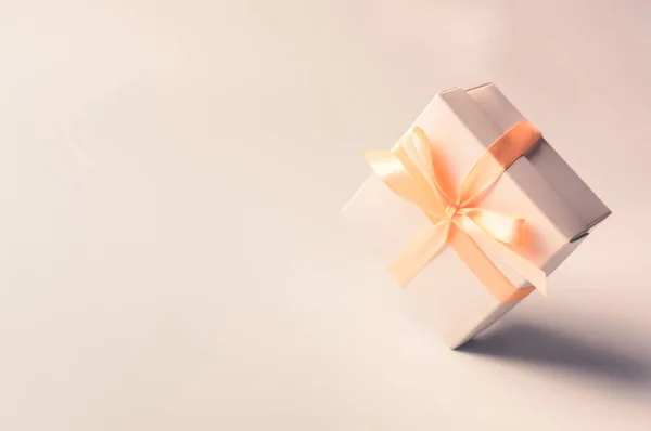 Geschenkdoos met beige lint op een witte ondergrond, isoleren. nul zwaartekracht. levitatie. Kopieerruimte. Het concept van verkoop, kortingen, kerstcadeaus en winkelen. — Stockfoto