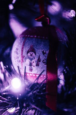 Neon mavi ışıkta süslenmiş Noel ağacı. Kardan adamla oyuncak top ve fenerli çelenk. Bokeh 'le yılbaşı hediyesi makro fotoğraf. Kış tatili hafif dekorasyonu
