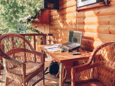 Üzümlerin altında hasır mobilyalar olan açık bir alanda işyeri. Serbest çalışanlar için bir yer. Ücretsiz çalışma kavramı.