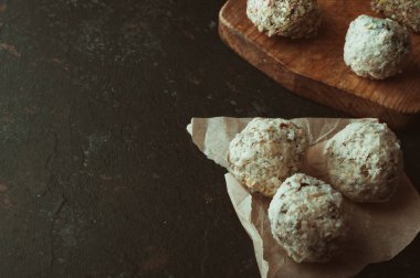 Sağlıklı çikolata enerji ısırıkları, fındıklar, tarihler, ahşap bir masada hindistan cevizi taneleri. Ev yapımı vejetaryen glütensiz sağlıklı atıştırmalıklar. Kırsal stil tonlama. Boşluğu kopyala.